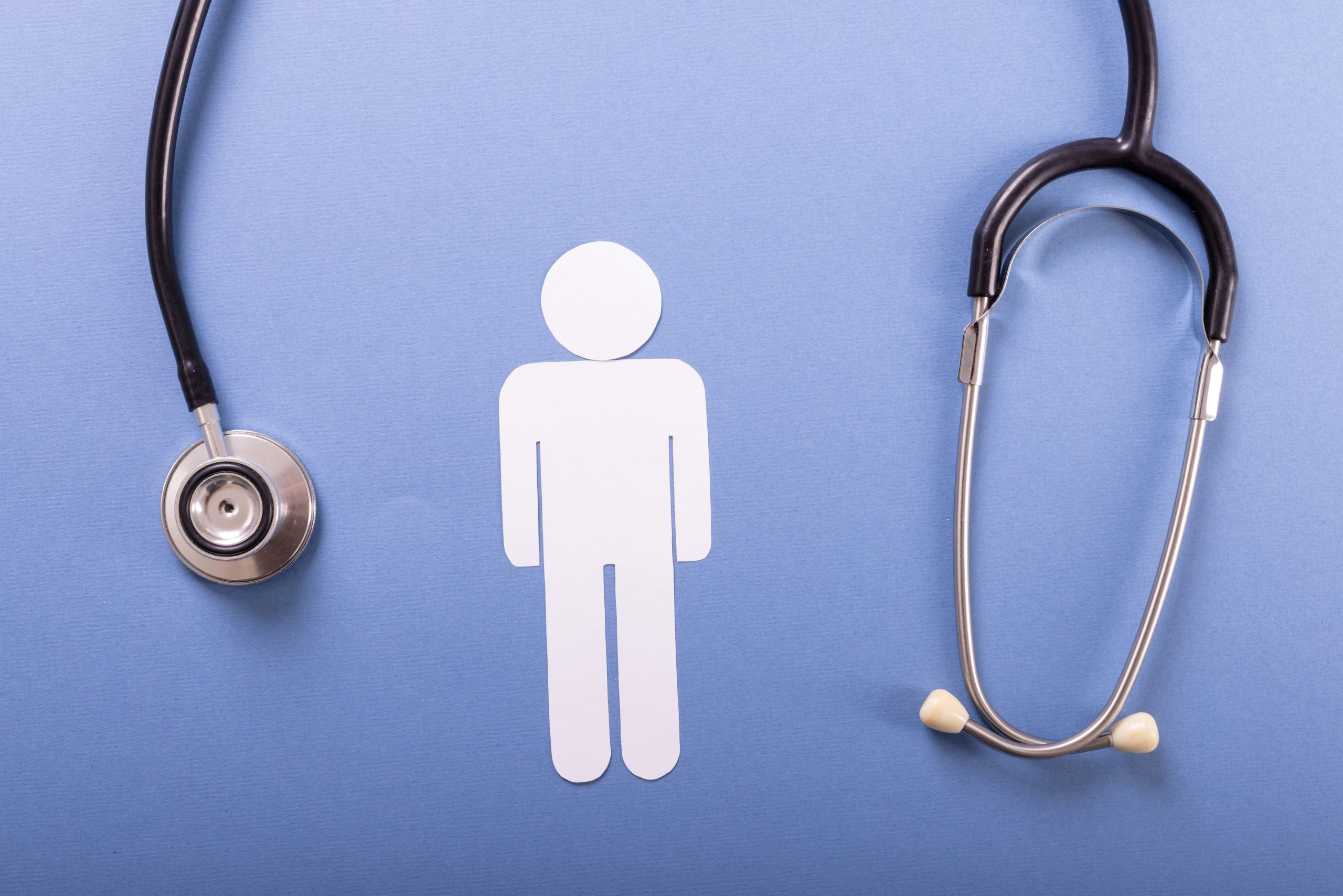 Directly above shot of stethoscope with paper man against blue background, copy space. medical, male, disease, test and healthcare concept.